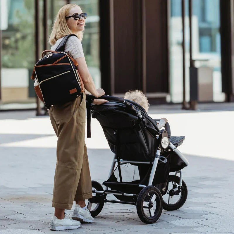 Frau mit stilvoller Wickeltasche von Doveta beim Spaziergang mit Kinderwagen