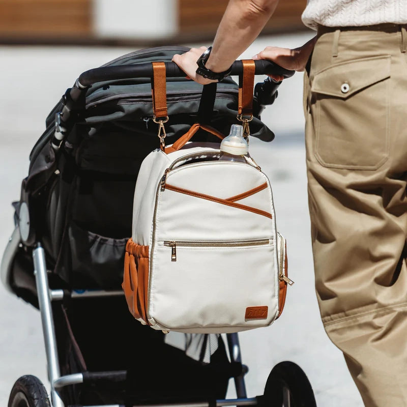 Beige Wickeltasche mit cognacfarbenen Lederdetails, befestigt am Kinderwagen – Doveta.de Wickeltaschen-Kollektion